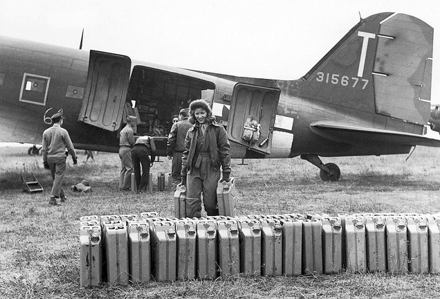 A US Army nurse helps unload jerry cans of gasoline from a C-47 near Reims, France in 1944. (US Army)